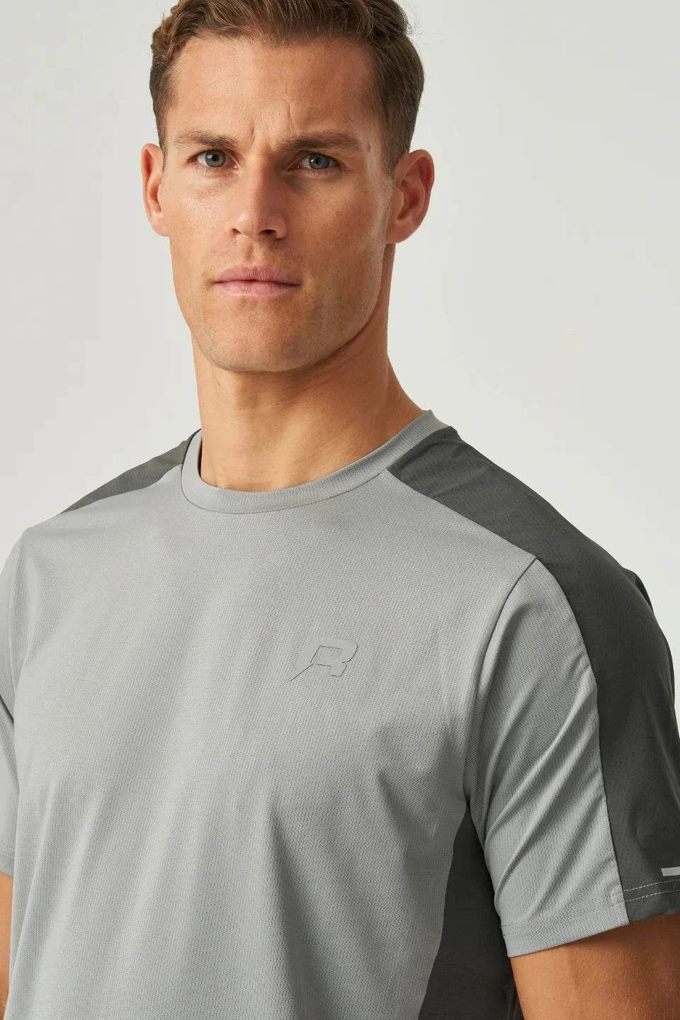 Male model wearing Reprimo Nova T-Shirt in slate and marble with duo-tone design, heat-sealed seams, and reflective detailing for athletic performance