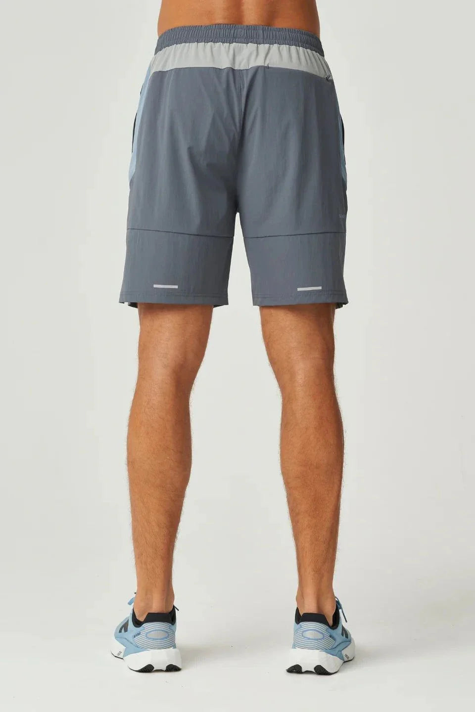 Back view of dusky blue Reprimo Vortex Shorts with adjustable waistband and ergonomic panel detailing worn by male model