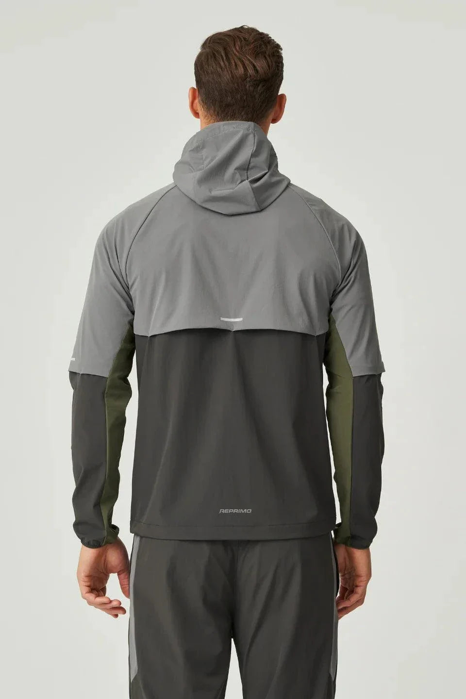 Back view of man wearing Reprimo Vortex Windbreaker in olive and dark grey with ergonomic fit and reflective details