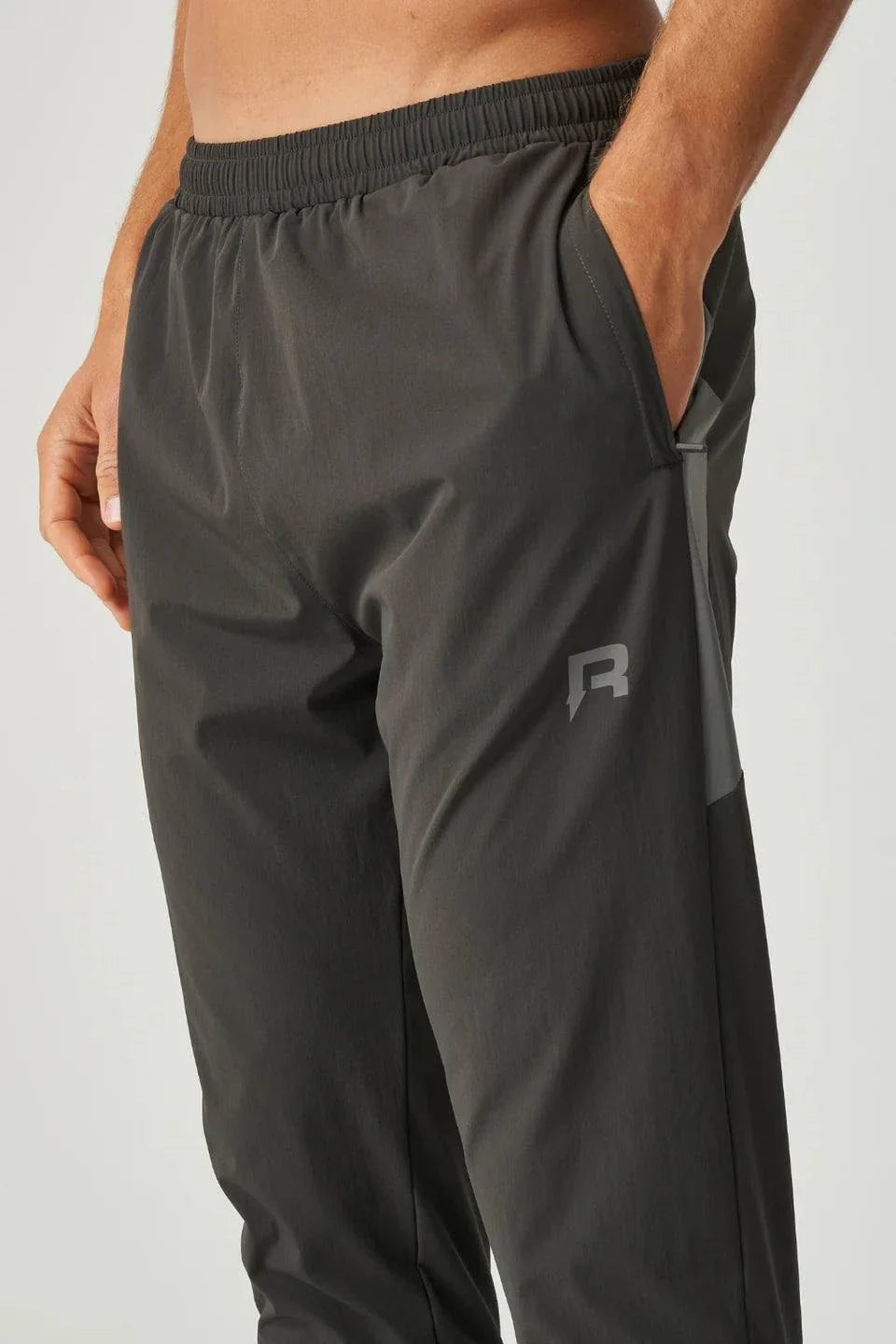 Close-up of olive and dark grey Reprimo Vortex Pants with ergonomic paneling and adjustable waistband for active wear