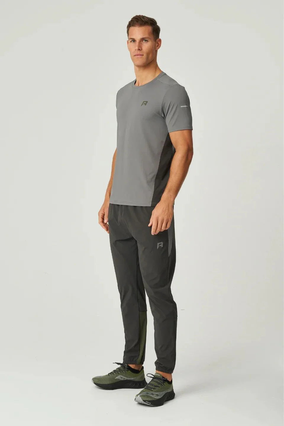 Man wearing Reprimo Vortex Pants in olive and dark grey with ergonomic and adjustable features.