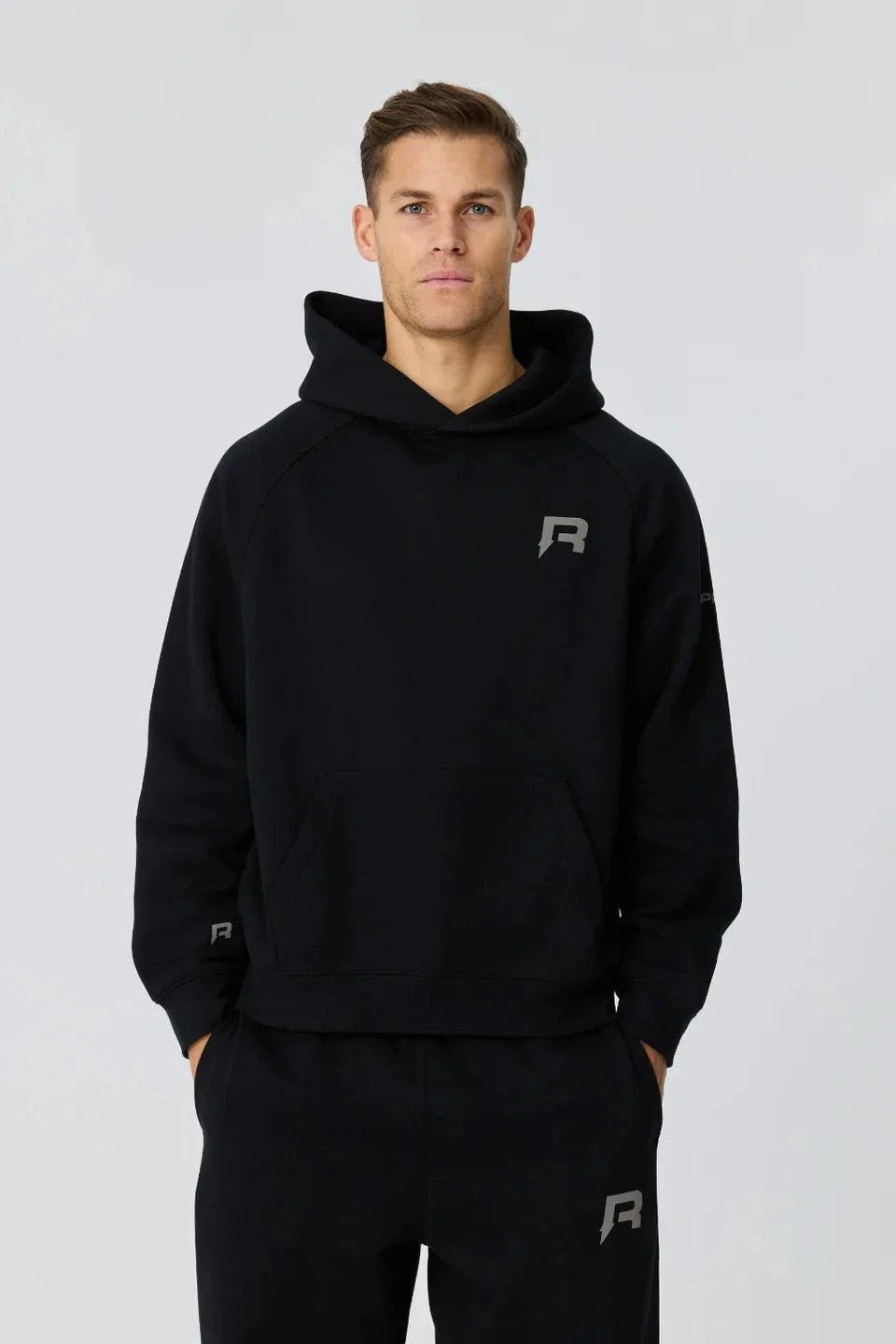 Man wearing black Reprimo Collective Hoodie with reflective logo, soft brushed-back fabric, and ergonomic fit