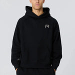 Man wearing black Reprimo Collective Hoodie with reflective logo, soft brushed-back fabric, and ergonomic fit