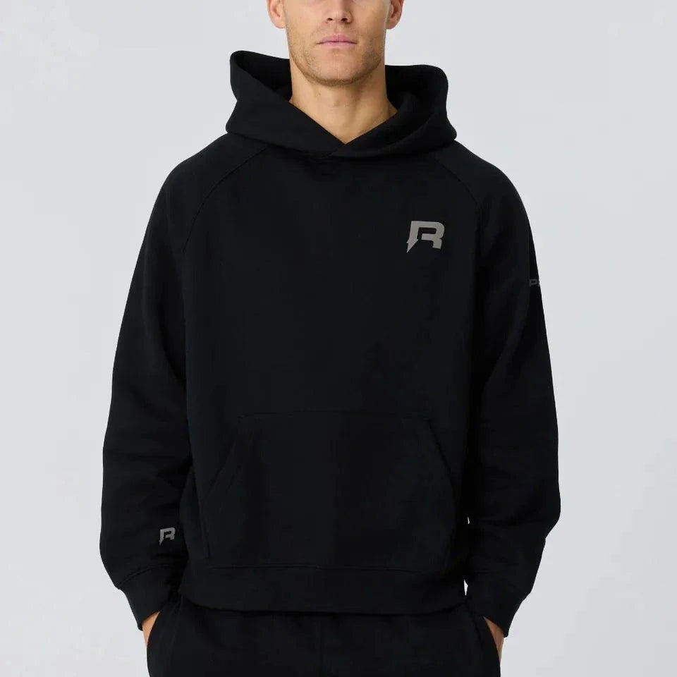 Man wearing black Reprimo Collective Hoodie with reflective logo, soft brushed-back fabric, and ergonomic fit