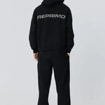 Back view of person wearing black Reprimo Collective Hoodie with reflective logo and ergonomic fit.