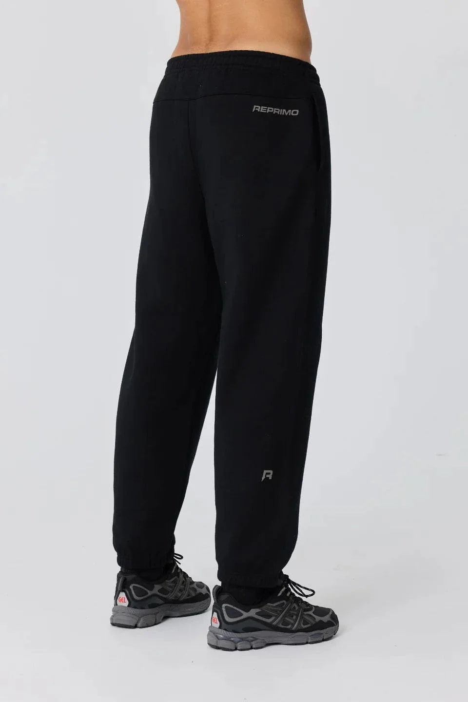 Black Reprimo Collective Joggers with brushed-back jersey fabric, ergonomic fit, adjustable waistband, and reflective branding details.