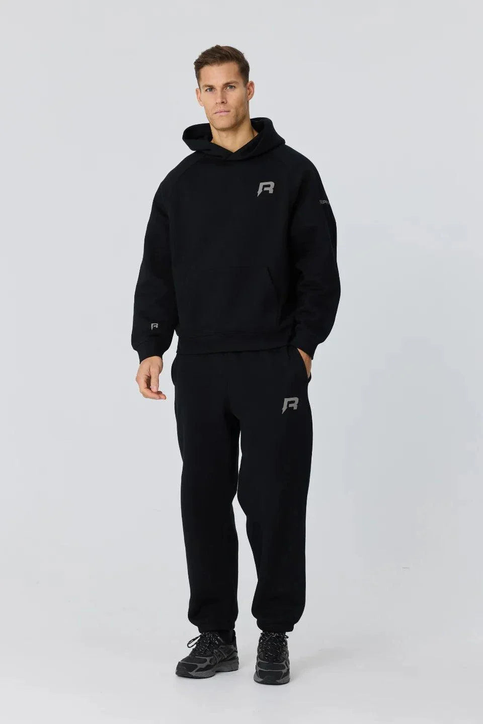 Man wearing black Reprimo Collective Joggers with adjustable waistband and reflective branding.