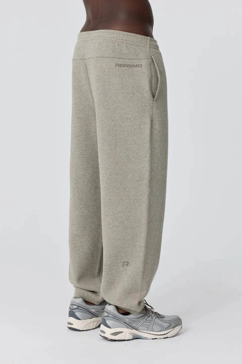 Side view of person wearing grey Reprimo Collective Joggers with adjustable waistband and reflective branding