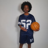 Woman wearing navy Five Questions Mesh Football Shorts and jersey holding basketball
