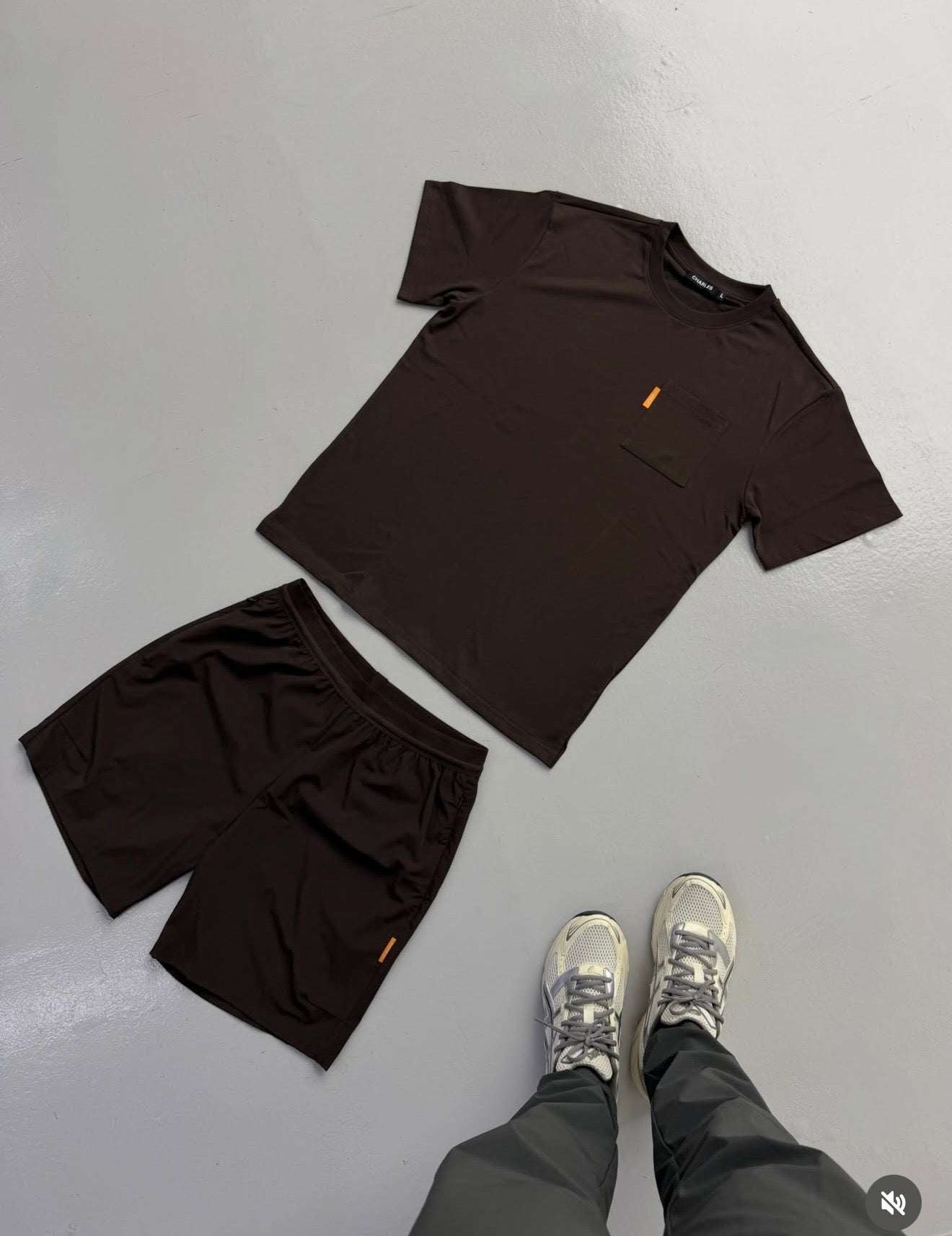 Studio Pocket Tee by Charles Brown Studio hanging on wooden hangers against white background