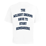 White t-shirt with navy text "The Wildest Dreams Have to Start Somewhere" on the back