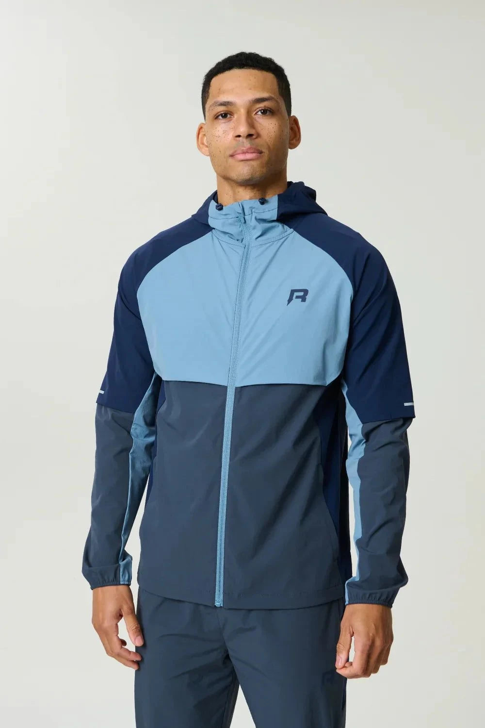Reprimo Vortex Windbreaker dusty blue with ergonomic design and reflective details, lightweight wind-resistant jacket