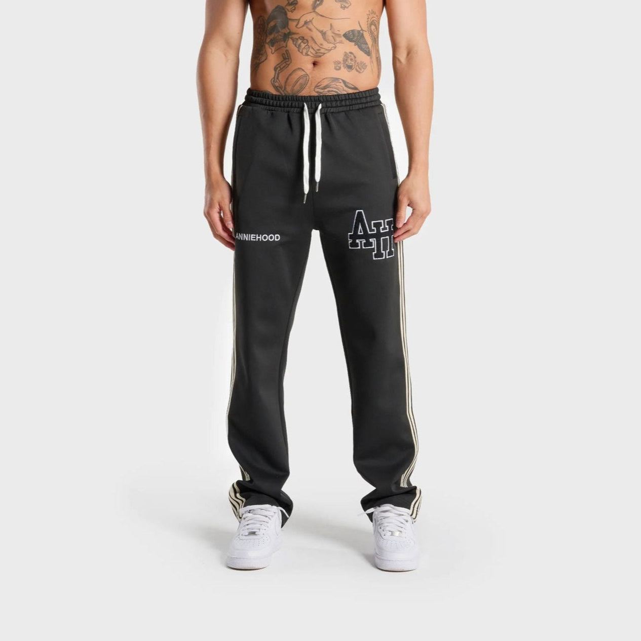 Front view of a person wearing black ANNIE HOOD track pants with white side stripes and drawstring waist