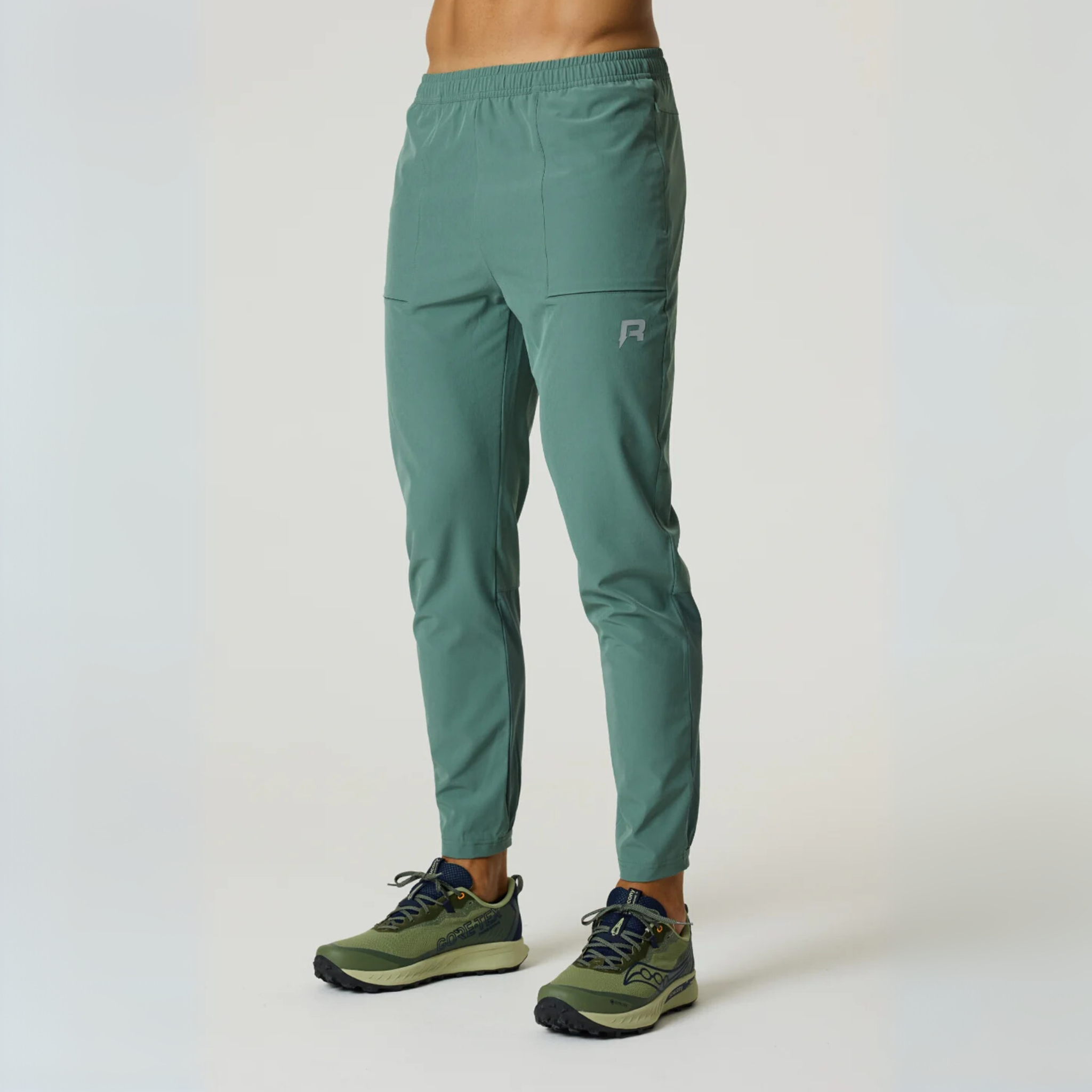 Reprimo Glide Pants in botanical pine with tapered fit, breathable textured fabric, secure seam pockets, and elasticated back cuffs for flexible comfort.