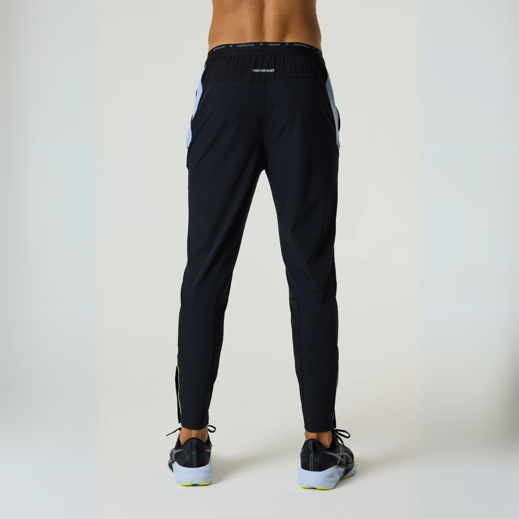 Rear view of a person wearing black Reprimo Flight Pants with dusky sky accents, featuring reflective strips and a comfortable, sporty fit.