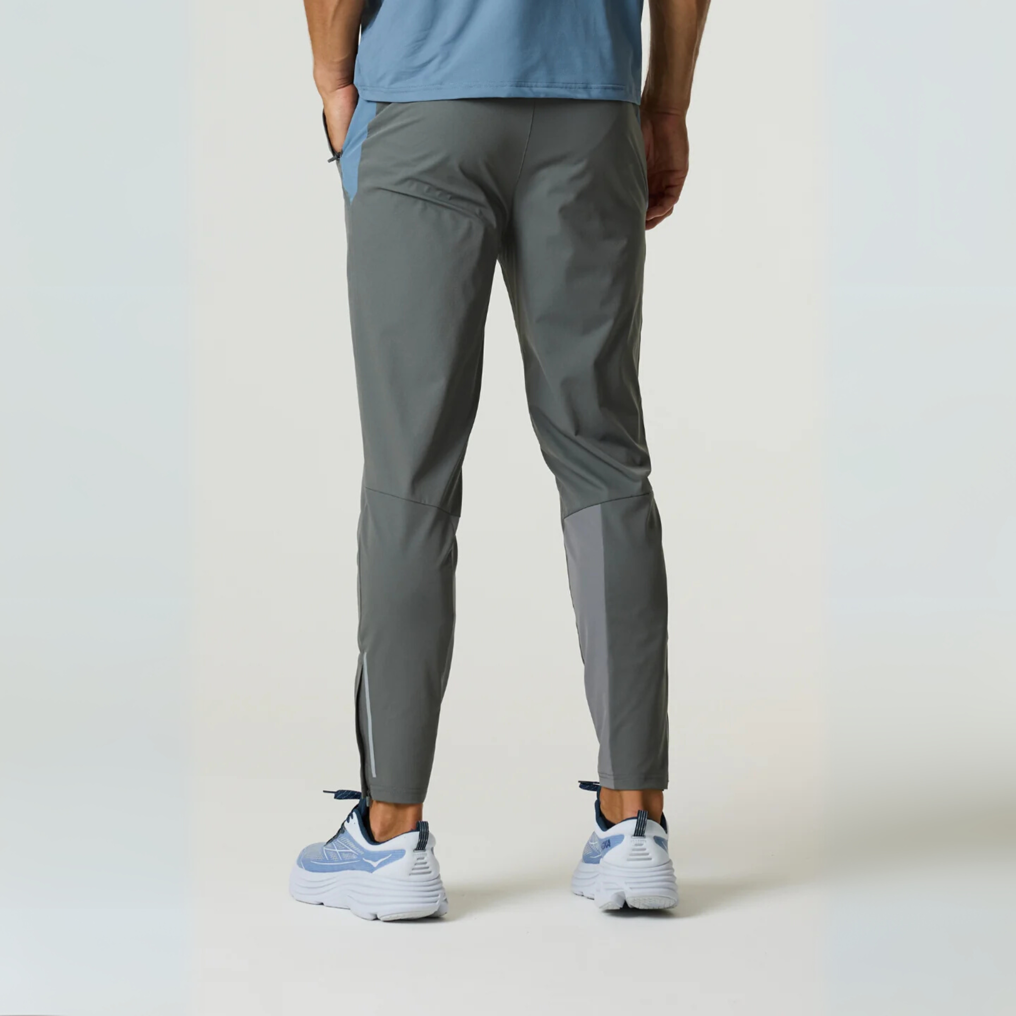 Back view of a person wearing Reprimo Flight Pants in Air Force Blue and Gunmetal with reflective strips, designed for performance and comfort.