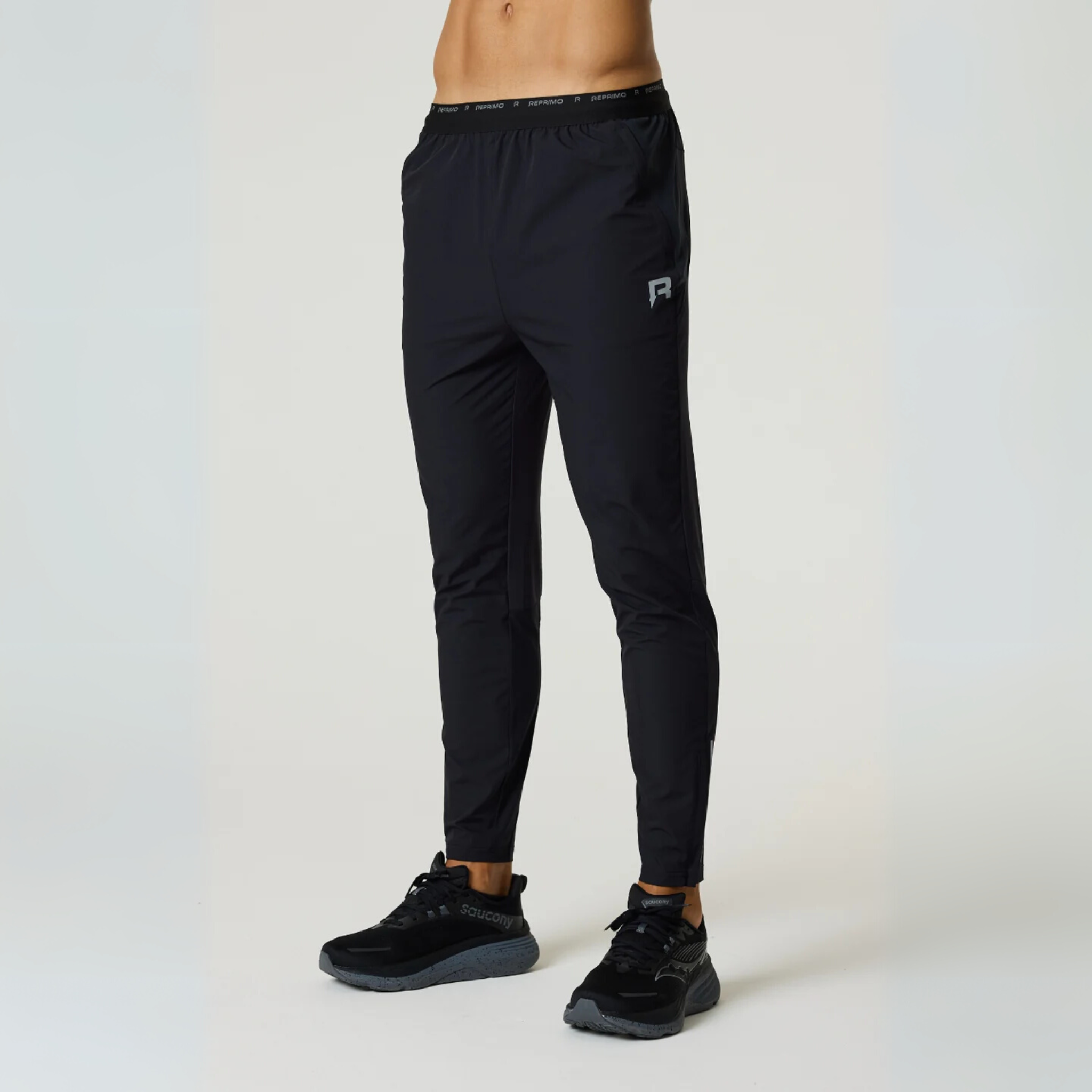 Black Reprimo Flight Pants with tapered fit, elastic waistband, and reflective details designed for athletic performance and comfort.