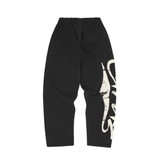 Corteiz Woosh black sweatpants with open hem and graphic print on leg