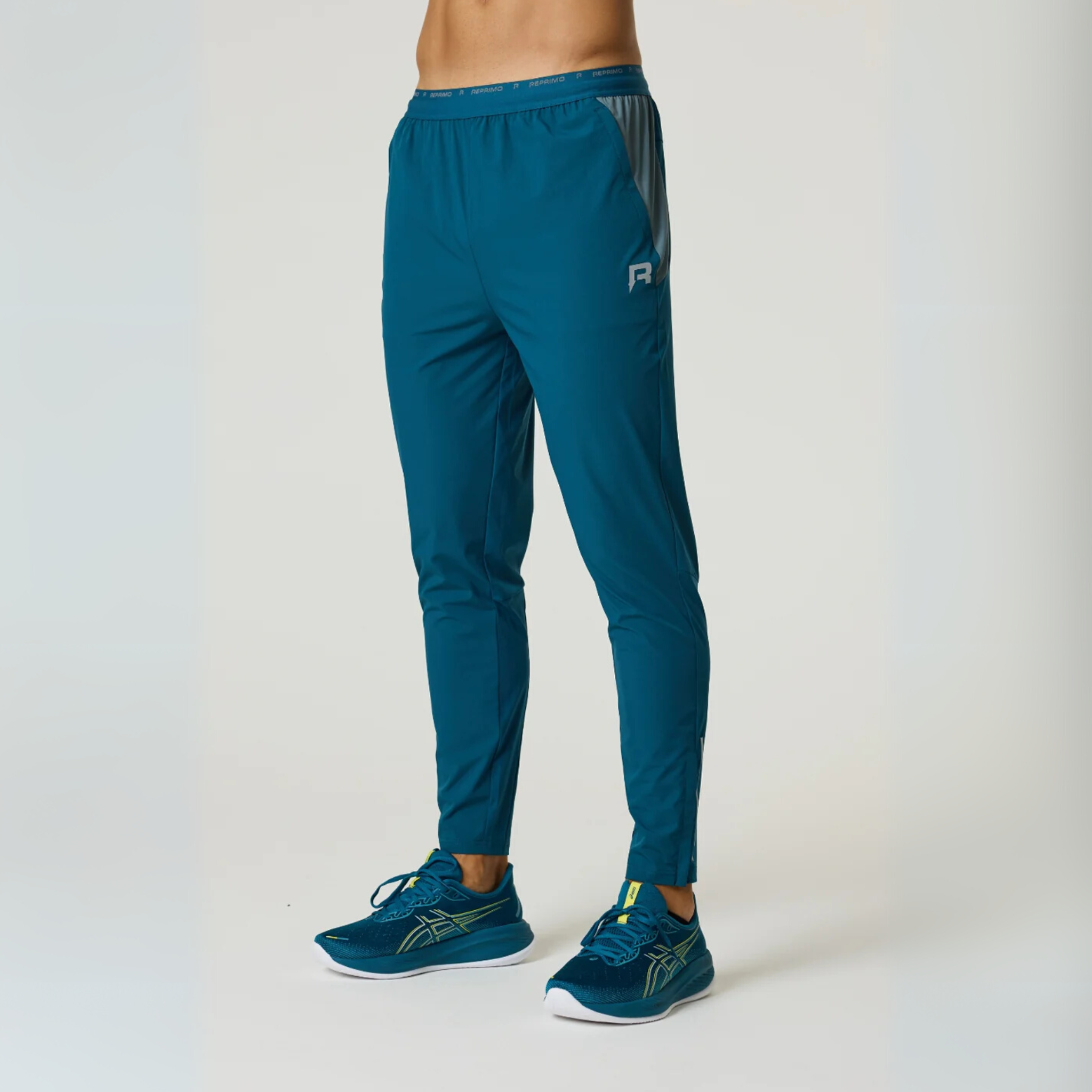 Reprimo Flight Pants in tidal teal and blue steel with breathable fabric, reflective strips, and secure side pockets for athletic performance and comfort.