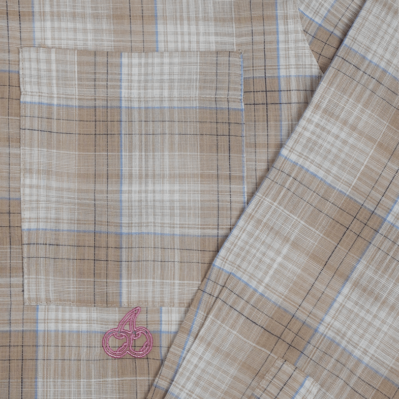 Close-up of Cherry Location Beige Shirt showing beige plaid fabric with blue and brown lines and a pink cherry logo on the pocket