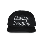 Black cap with white embroidered Cherry Location text front embroidered design
