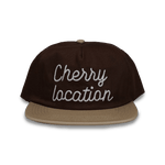 Brown Cherry Location cap with beige brim and embroidered text