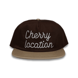 Brown Cherry Location cap with beige brim and embroidered text