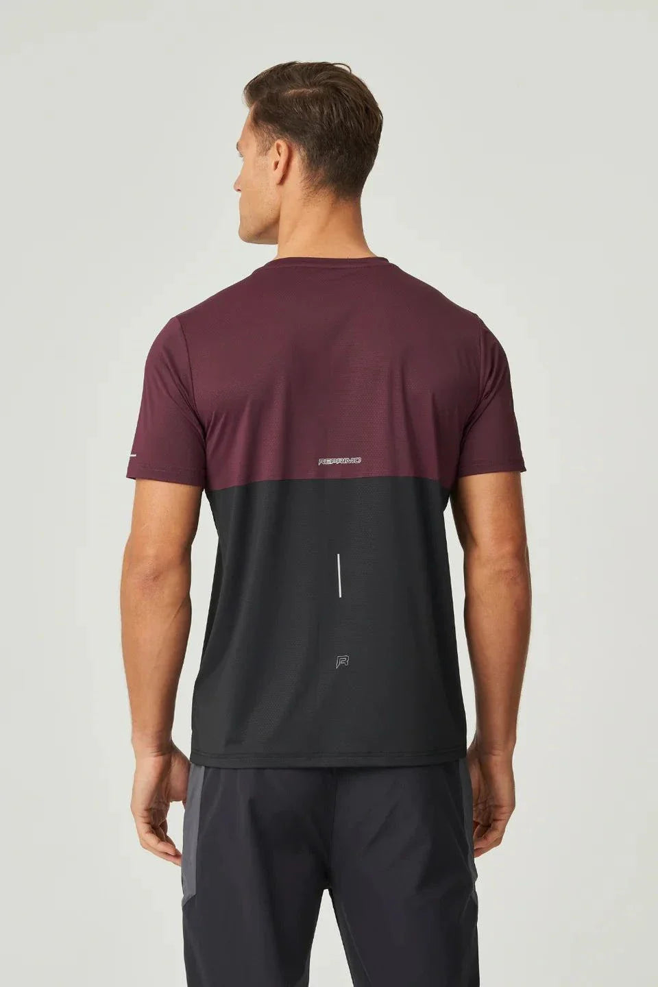 Back view of man wearing burgundy and obsidian Reprimo Impact T-Shirt with ergonomic fit and color pop accents