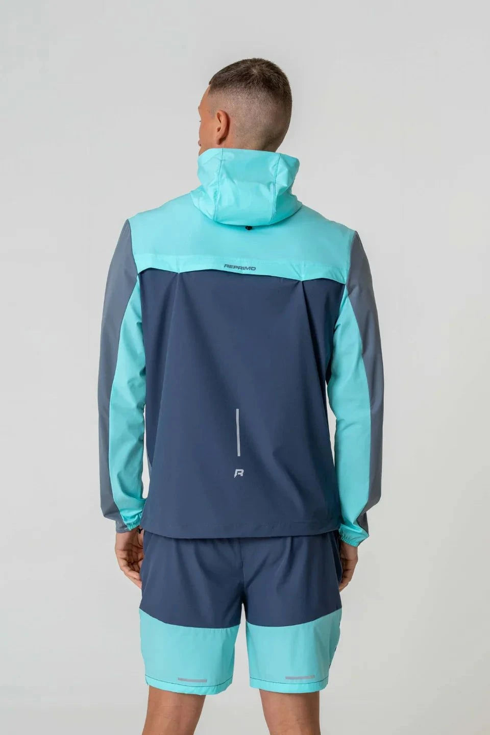 Reprimo Flight Windbreaker in cyan and navy, back view.