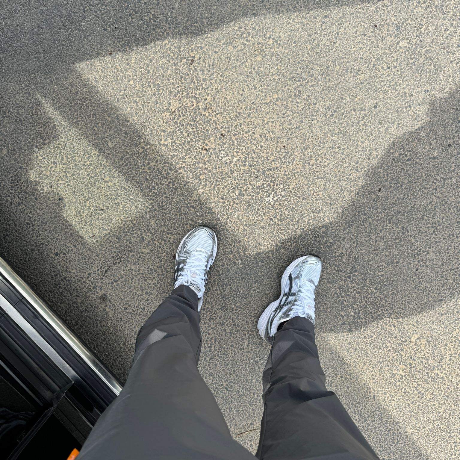 Studio By Charles charcoal grey trackpants worn with white sneakers on pavement background