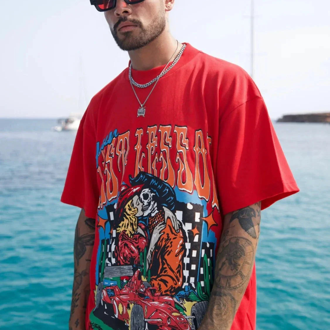 Last Lesson Fast Lane T-shirt in red with graphic design worn by a man near water.