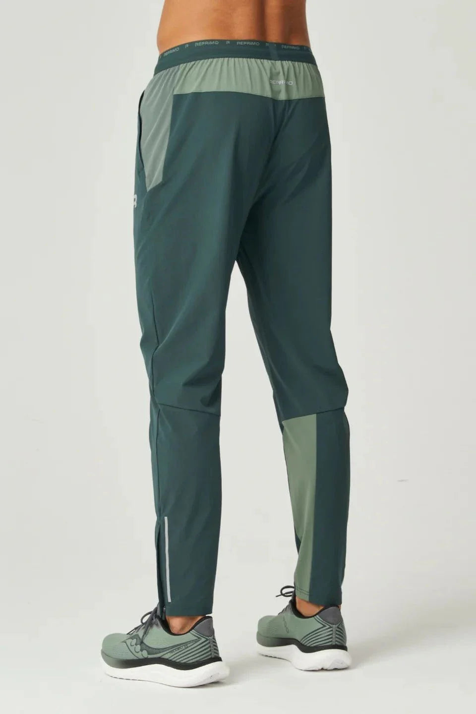 Back view of a person wearing Reprimo Flight Pants in hunter green and botanical with reflective strips and functional pockets