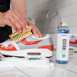 SneakersER Premium Cleaning Duo Kit with natural wood brush cleaning white and red sneaker next to 250ml bottle on tiled surface