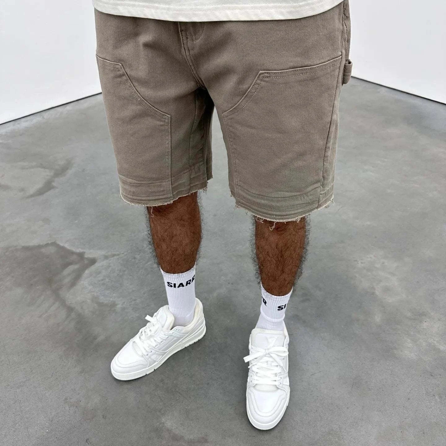 Beige Siarr Rio Shorts with rivet buttons, leather tab, and raw hem.