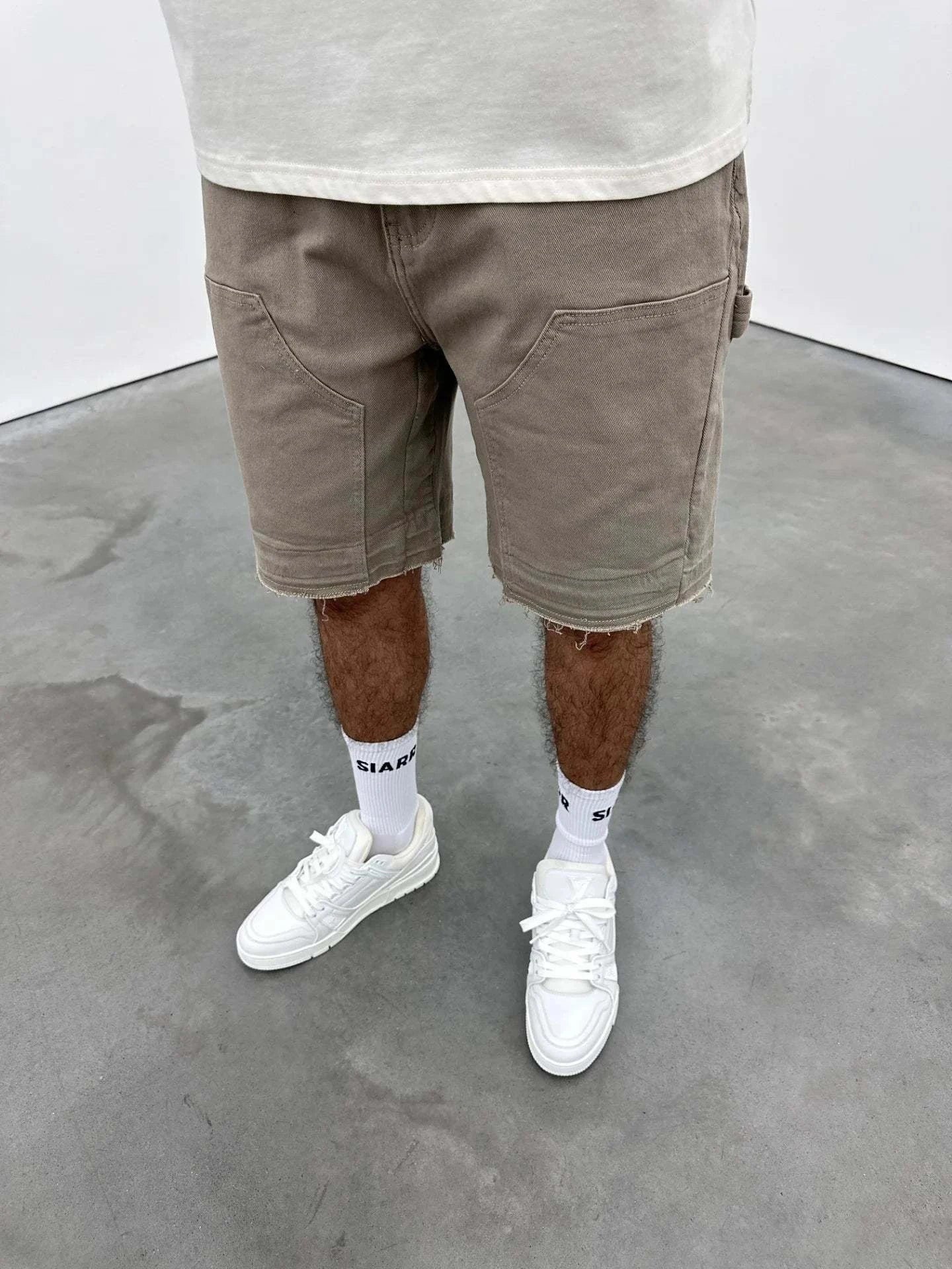 Beige Siarr Rio Shorts with rivet buttons, leather tab, and raw hem.