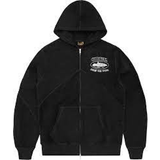 Corteiz Superior V2 black zip-up hoodie with logo design.
